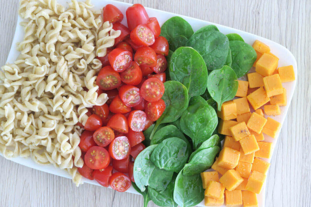 Salade de pâtes complètes, tomates cerises, épinards et mimolette